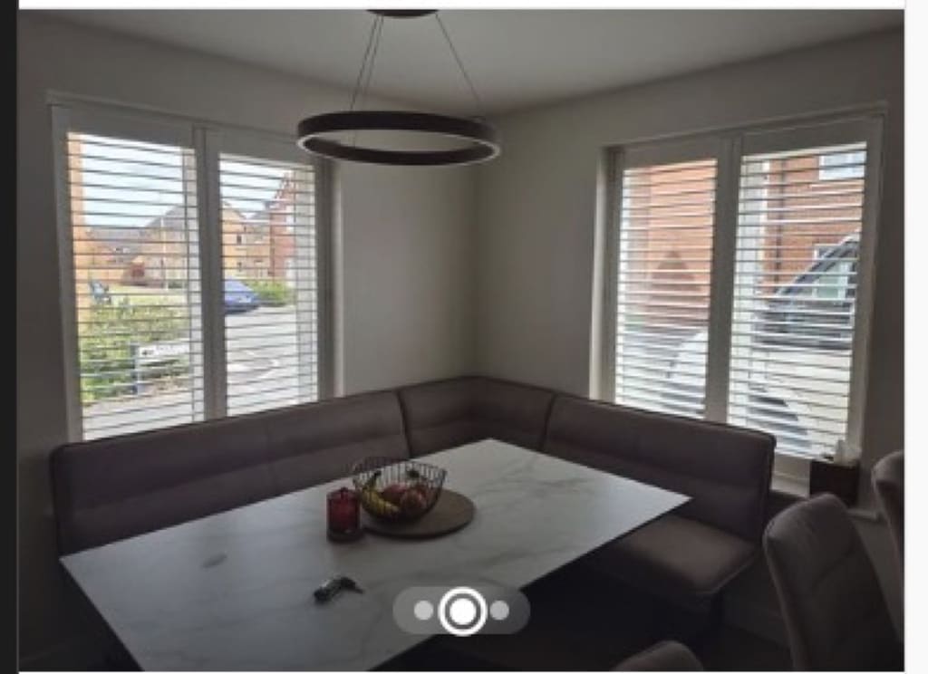Pure White full height shutters on corner dining windows with louvres tilted open, marble dining table below
